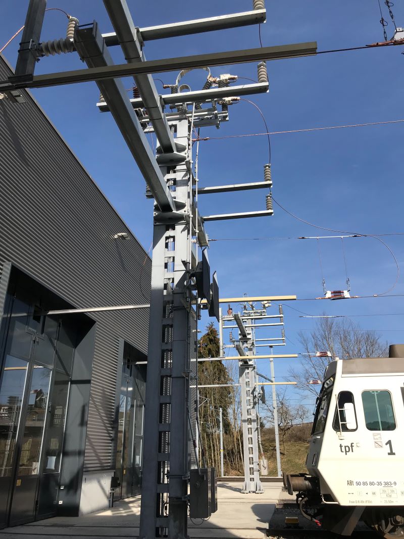 Depot der Freiburgischen Verkehrsbetriebe (TPF) in Givisiez: Abfangmasten vor Depot mit Schaltgeräten, Motorantrieben und Signalen Bedienstelle der Fahrleitungssteuerung (Bild: Furrer+Frey).