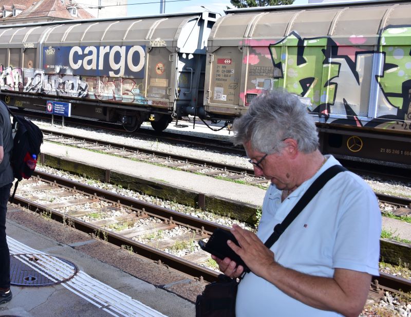 Dieser Herr schaut auf seinem Smartphone nach der Abfahrtszeit, aber nicht, wie das Bild vermuten lassen könnte, für den Güterzug, sondern für den Zug, der bald hier in Estavayer-le-Lac (am Neuenburgersee) eintreffen wird. Jetzt noch das Billett lösen und in Kürze wird abgefahren (Bild: Johannes von Arx).